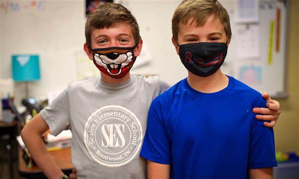 Two students smile for photos